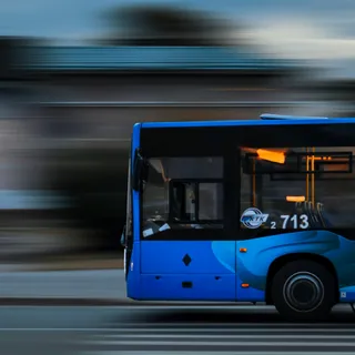 A blue bus traveling through a city street