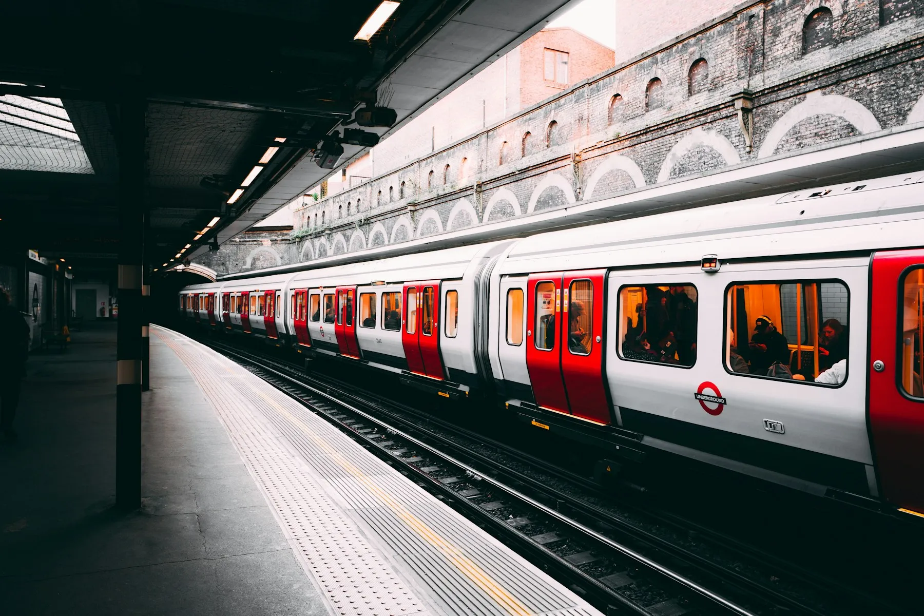 A red and white train passing an urban station