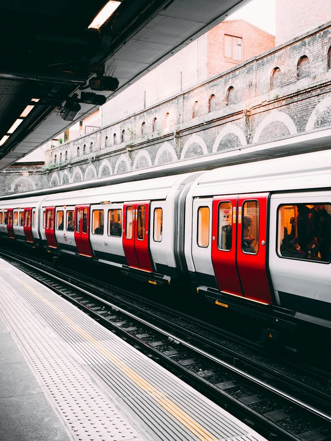 A red and white train passing an urban station