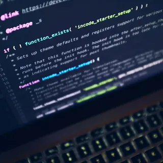 A laptop computer glowing on a dark work surface